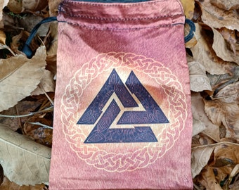 Puede incluir: Una bolsa de cordón roja con un símbolo Valknut dorado y negro en un diseño circular. La bolsa está hecha de una tela suave y sedosa.