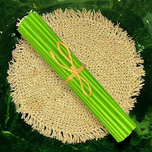 May include: A bundle of green straws tied together with twine, resting on a brown crocheted round mat.