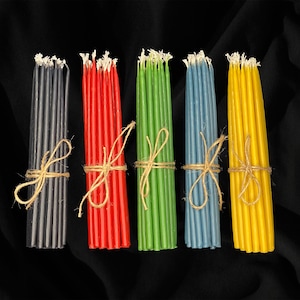 May include: Six bundles of birthday candles in various colors, including black, red, green, blue, and yellow. Each bundle is tied with twine.