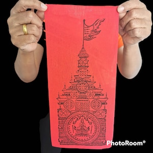 May include: A red fabric with a black and white image of a pagoda with a flag on top. The pagoda is surrounded by intricate designs and symbols.