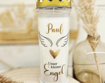 Può includere: Una candela bianca in un barattolo di vetro trasparente con coperchio dorato. La candela ha il nome "Paul", ali d'angelo e un cuore dorato. Le parole "Unser kleiner Engel" sono stampate anche sul barattolo.