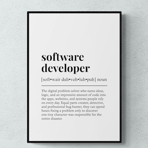 May include: A framed wall art print featuring a dictionary-style definition of the term software developer. The text is printed in black on a white background, including the phonetic pronunciation and a descriptive paragraph about the role.