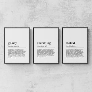 Op de afbeelding: Drie ingelijste wandposters met woordenboekdefinities van de surftermen gnarly, shredding en stoked. Elke print bevat zwarte tekst op een witte achtergrond, gepresenteerd in dunne zwarte lijsten, horizontaal naast elkaar geplaatst.