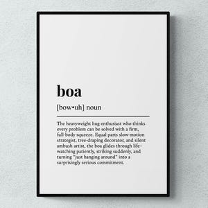 May include: A framed print featuring the word "boa" in a bold black font, followed by a definition. The text is centered on a white background, enclosed within a black frame, ideal for interior decoration.
