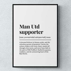 May include: A framed print with the words "Man Utd supporter" in black, with a definition below. The definition describes a devoted believer in history, pride, and the relentless pursuit of greatness.