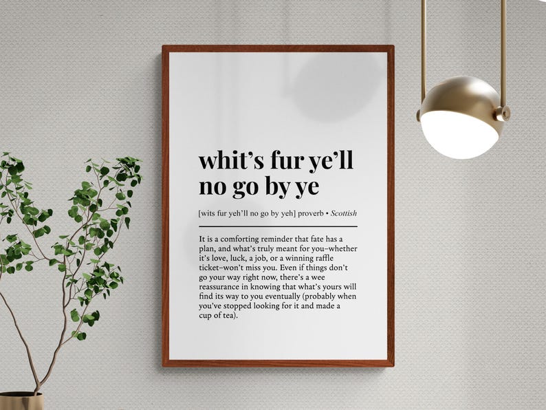May include: A framed print with the text "whit's fur ye'll no go by ye", a Scottish proverb. The print has a white background with black text and a brown frame. The text is a comforting reminder about fate.