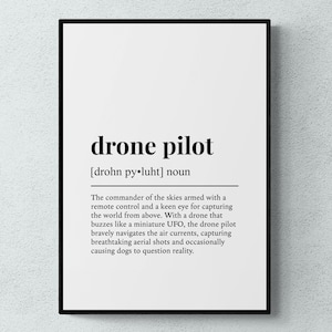 May include: A framed wall art print featuring a dictionary-style definition of the term drone pilot. The text includes the phonetic pronunciation, the noun classification, and a descriptive paragraph about operating a drone from above.