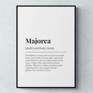 May include: A framed print with the word "Majorca" in bold black text. Below, the phonetic pronunciation is given. The definition describes the Balearic island's beauty, including mountain roads, coves, paella, resort buzz, and sunshine.