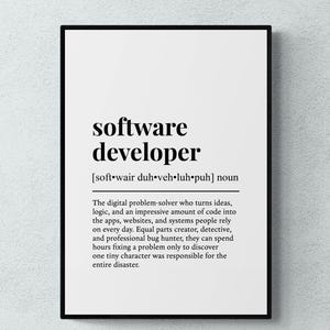 May include: A framed wall art print featuring a dictionary-style definition of the term software developer. The text is printed in black on a white background, including the phonetic pronunciation and a descriptive paragraph about the role.