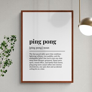 Puede incluir: Un marco con la definici&oacute;n de "ping pong" en texto negro sobre fondo blanco. La definici&oacute;n describe el ritmo r&aacute;pido del deporte y las aspiraciones ol&iacute;mpicas. El marco es de color marr&oacute;n oscuro.