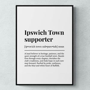 May include: A framed print with the words "Ipswich Town supporter" in bold black font. Below the title is a phonetic pronunciation and a definition. The text describes a loyal believer in the football club's traditions.
