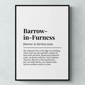 May include: A framed print featuring the words "Barrow-in-Furness" in a black, bold font. The definition below describes the shipyard town, its industrial pride, and resilience. The print is displayed against a light grey textured wall.