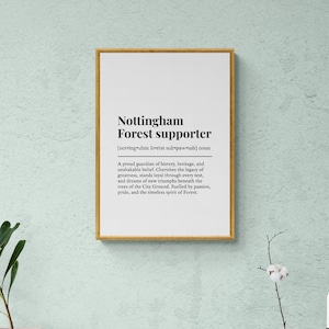 May include: A framed print with the text "Nottingham Forest supporter" in black font on a white background. The frame is gold-colored. The text includes a definition and a description of a supporter.