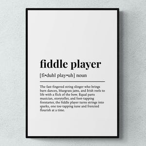 Puede incluir: Impresión enmarcada con la palabra "fiddle player" en negro. La definición describe a un músico que toca bailes de granero, jams de bluegrass y reels irlandeses. La impresión está sobre un fondo blanco.