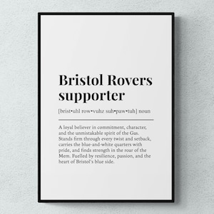 May include: A black framed print featuring the words "Bristol Rovers supporter" in a bold font. The definition below describes a loyal believer in the team's spirit. The text is on a white background.