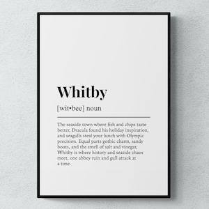 Könnte beinhalten: Gerahmter Druck mit dem Wort "Whitby" in fetter schwarzer Schrift, gefolgt von einer Definition. Die Definition beschreibt Whitby als Küstenstadt mit gotischem Charme und Geschichte. Der Druck hat einen weißen Hintergrund.