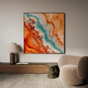 Puede incluir: Impresión artística abstracta con una paleta de colores vibrantes. La obra presenta una mezcla de tonos naranja, turquesa y blanco, creando un paisaje dinámico y texturizado. La pieza está enmarcada en un borde dorado, añadiendo un toque de elegancia al diseño moderno.