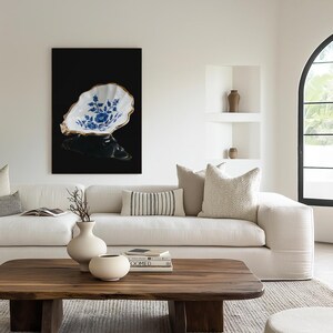 May include: A decorative ceramic oyster shell-shaped bowl with a gold rim and blue floral design. The bowl is displayed against a black background, creating a striking contrast. This elegant piece adds a touch of sophistication to any home decor.