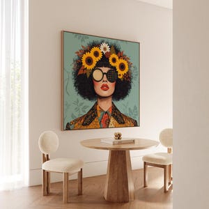 Puede incluir: Una impresión artística enmarcada que presenta a una mujer con una corona de girasoles y gafas de sol estampadas. La obra de arte se exhibe sobre una mesa de madera y dos sillas con tapicería color crema. La habitación tiene una paleta de colores neutros.