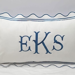 May include: A rectangular white pillow with a scalloped edge and navy blue trim. The pillow features the embroidered letters "EKS" in navy blue. The pillow is designed for decorative use.