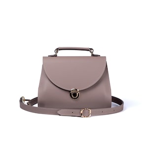Gray leather crossbody bag with handle and gold push-lock clasp on white background.