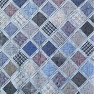 May include: A blue and white patchwork quilt with a diamond pattern. The quilt is made of different fabrics, including plaid, striped, and solid colors.