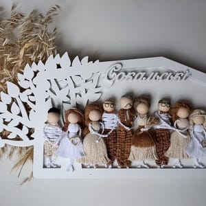 May include: White wooden sign with a cutout tree design and the text "Gokalsky" at the top. Ten small yarn dolls are arranged in a row below the tree, representing a family.
