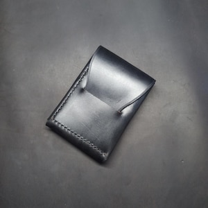 Black edc wallet with flap and quick access slot.