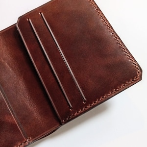 Cartera de piel marrón con ranuras para tarjetas horizontales y verticales.