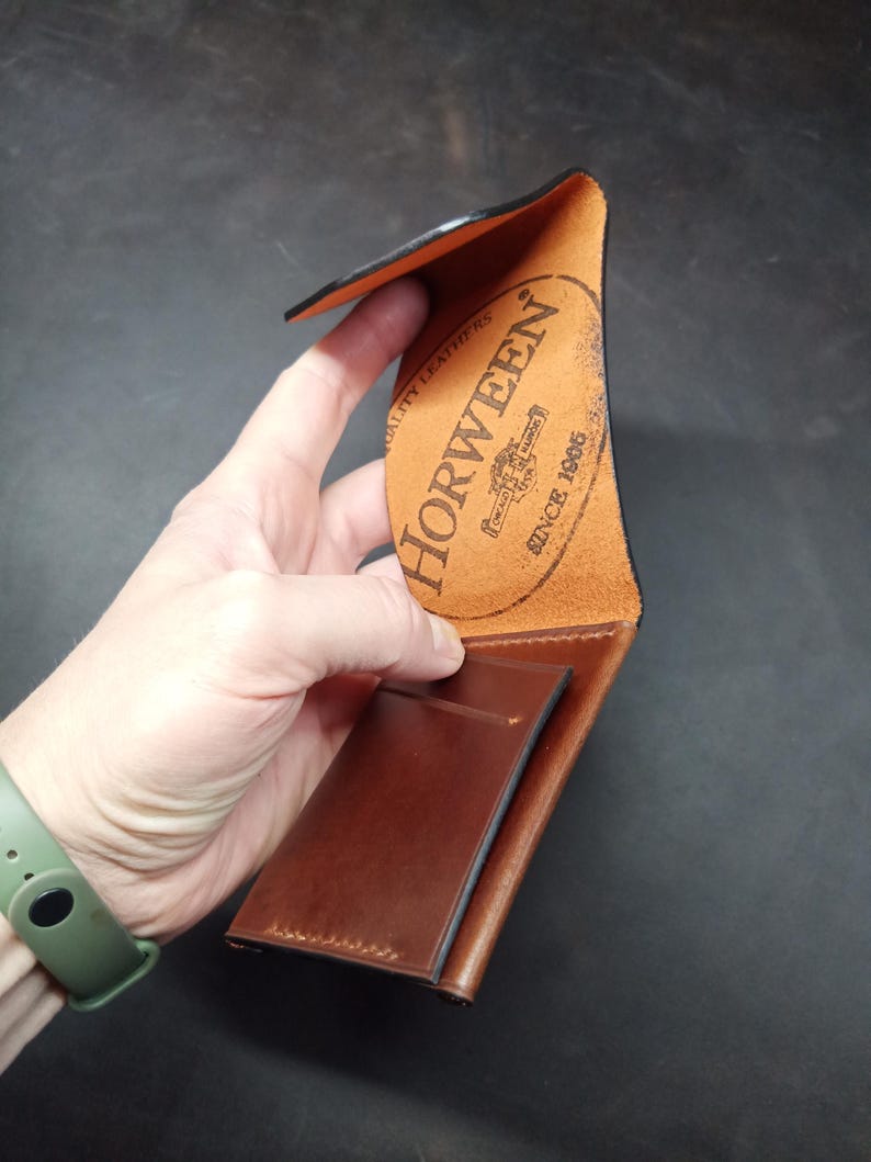 May include: A brown leather wallet with a Horween leather label. The label is orange and has the text "Horween" and "Since 1905" in black.