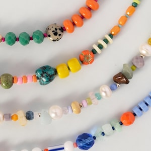 Peut inclure: Gros plan de plusieurs colliers de perles colorées. Les colliers présentent une variété de perles de différentes formes, tailles et couleurs, notamment orange, vert, jaune, bleu et blanc. Certaines perles ont des motifs et des textures uniques.