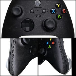 May include: Black Xbox controller with colorful A, B, X, and Y buttons. The controller has two joysticks, a directional pad, and various function buttons. The text "NEED A WEAPON" is printed on the right side of the controller.