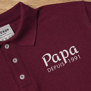 Puede incluir: Polo de color burdeos con un diseño bordado en blanco que dice "Papa Depuis 1991".