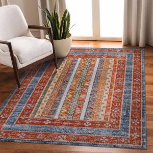 Peut inclure: Un tapis de salon bleu, orange et rouge à motifs géométriques. Le tapis a un aspect vieilli et est fait d'un matériau doux et durable.