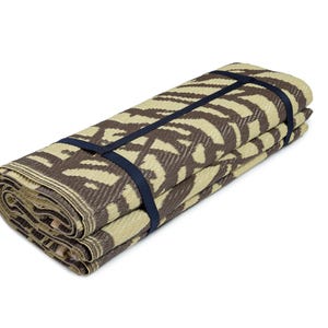 May include: A rolled up brown and beige patterned picnic mat with black straps.