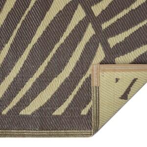 May include: Close-up of the edge of a brown and beige striped outdoor rug with a tan binding. The rug is made of woven material and has a textured surface.