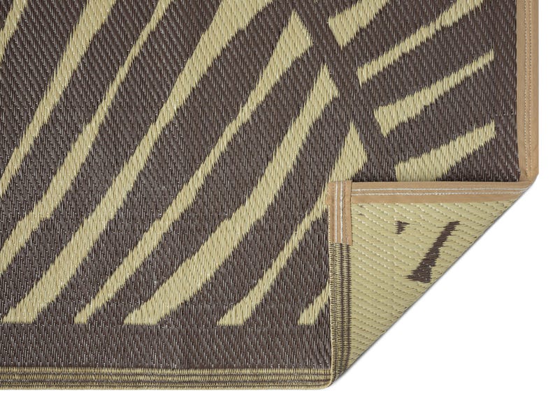 May include: Close-up of the edge of a brown and beige striped outdoor rug with a tan binding. The rug is made of woven material and has a textured surface.