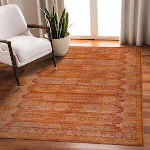 Pode incluir: Um tapete de área cor de ferrugem com um visual desgastado e vintage. O tapete tem um padrão sutil com uma borda.