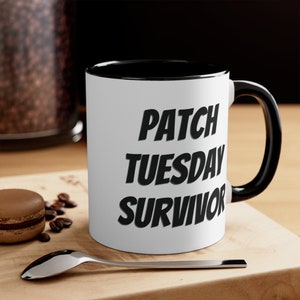 May include: White ceramic coffee mug with a black rim and handle. The mug has black text that reads "PATCH TUESDAY SURVIVOR".