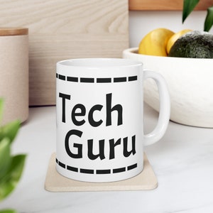 Puede incluir: Taza de cerámica blanca con un borde negro y el texto "Tech Guru" impreso en negro.