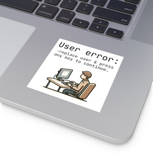 May include: A white sticker with a cartoon illustration of a person sitting at a computer. The text on the sticker reads "User error: -replace user & press any key to continue."