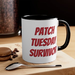 May include: White ceramic coffee mug with a black rim and handle. The mug has red text that reads "PATCH TUESDAY SURVIVOR".