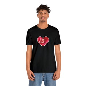 Könnte beinhalten: Ein schwarzes T-Shirt mit einem roten, pixeligen Herzen, auf dem in weiß "Tech Daddy" steht.