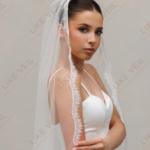 May include: A white bridal veil with a lace trim. The veil is worn over the head and shoulders. The text "LIKE VEIL" is visible in the background.