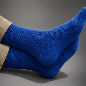 Op de afbeelding: Een paar fel koningsblauwe sokken met een fijn geribbelde breistructuur. De sokken reiken tot voorbij de enkel en worden gedragen met een beige broek, waarbij de gedetailleerde hielconstructie en het consistente blauwe garen zichtbaar zijn.
