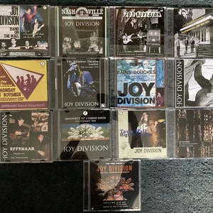 Puede incluir: Una colección de 10 discos compactos con Joy Division, una banda británica de post-punk. Los discos están en estuches de plástico transparente y muestran varias fechas y lugares de conciertos, incluyendo Nashville, Londres y Amsterdam.