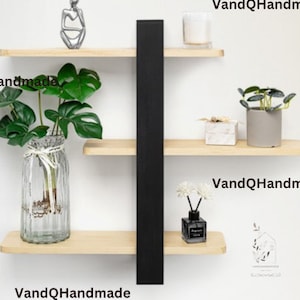 May include: Three wooden shelves with black metal supports, featuring decorative items such as a vase with a plant, a small sculpture, a candle, a small box, and a diffuser bottle. The shelves are mounted on a white wall. The text "VandQHandmade" appears on the bottom shelf.