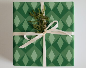 May include: A green gift box with a white diamond pattern is wrapped with a white ribbon and a sprig of greenery.