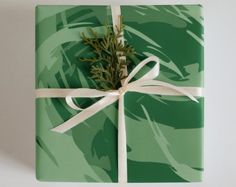 May include: A green gift box with a white ribbon and a small green sprig on top. The box has a green and white abstract pattern.