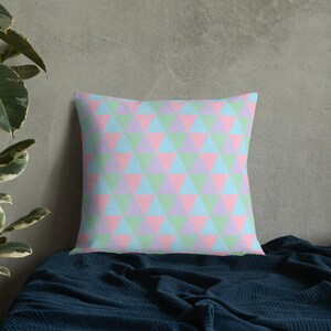 May include: A decorative throw pillow with a geometric pattern of pink, light blue and green triangles.